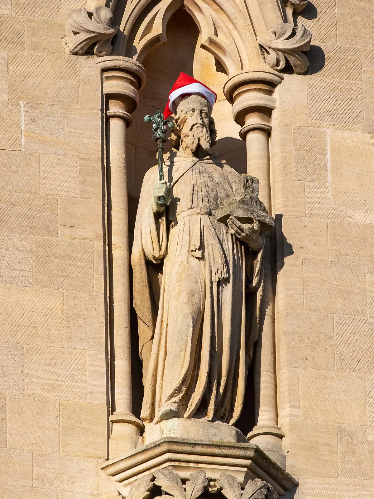 Santa Hats have been placed on Statues and a gargoyle on St Johns  College Chapel in Cambridge 