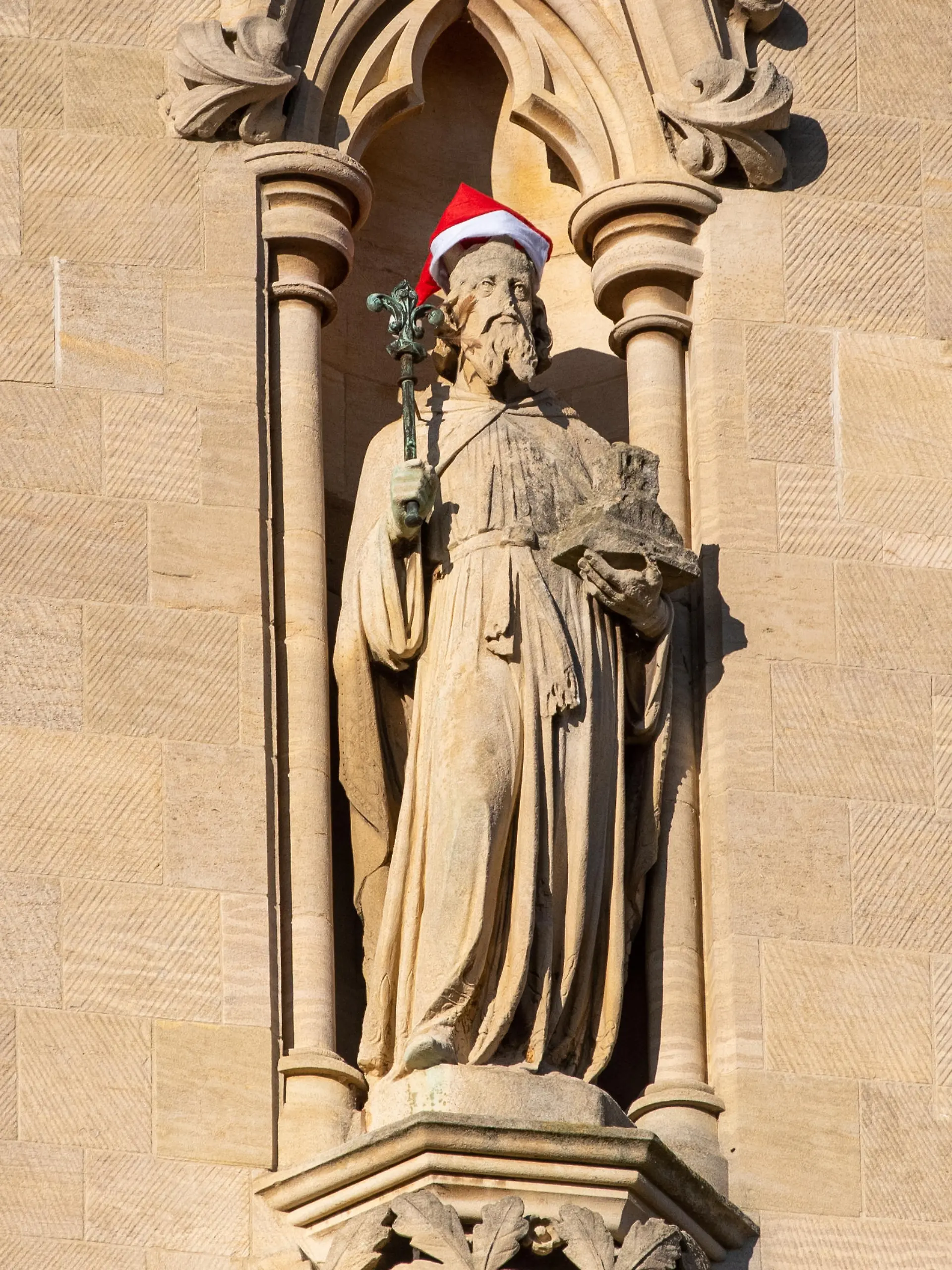 Santa Hats have been placed on Statues and a gargoyle on St Johns  College Chapel in Cambridge 