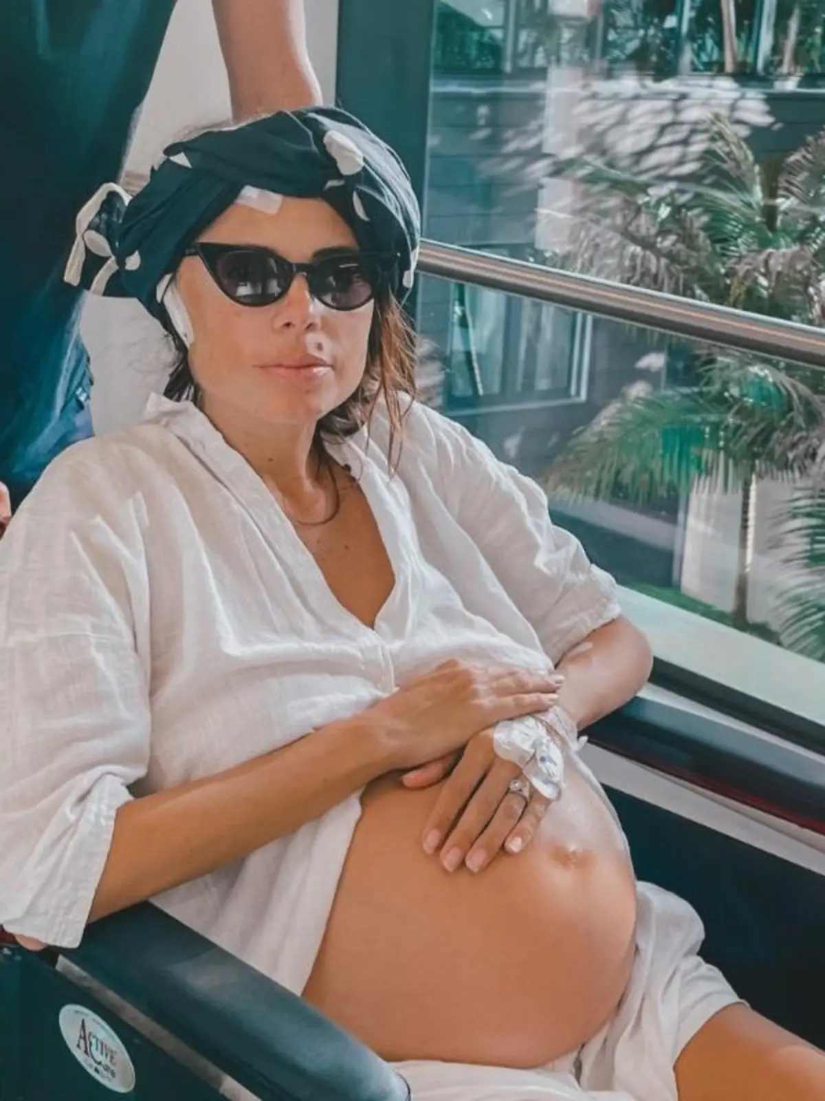 Elise wird in einem Rollstuhl geschoben während sie sich ihren Schwangerschaftsbauch hält.