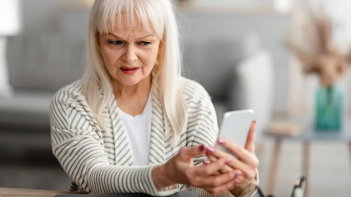 Suspicious Sms. Worried mature woman looking at smartphone screen, received bad news, got fishy scam message, doubtful confused lady holding gadget with concerned face expression, free copy space