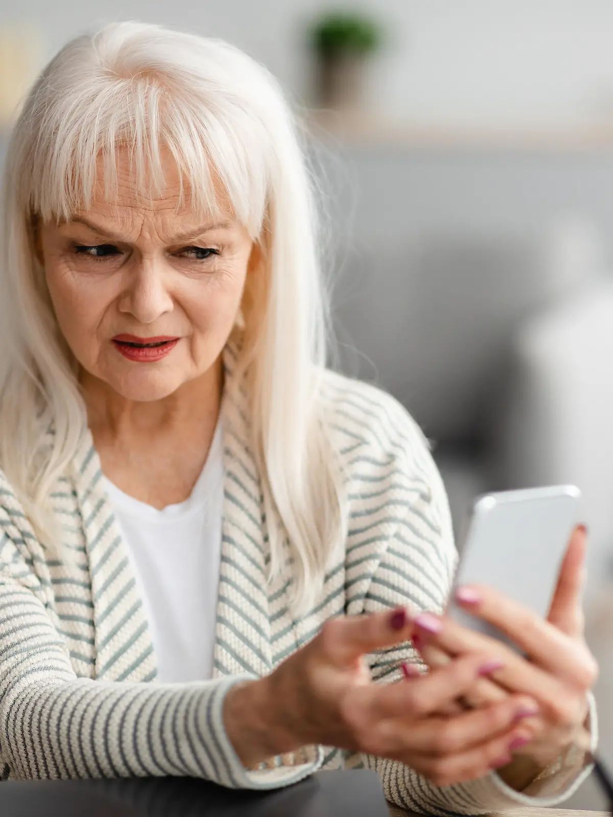 Suspicious Sms. Worried mature woman looking at smartphone screen, received bad news, got fishy scam message, doubtful confused lady holding gadget with concerned face expression, free copy space