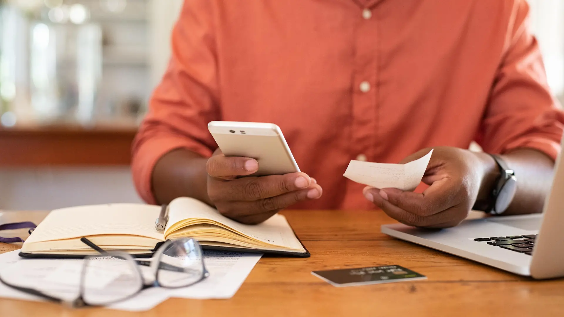 Closeup of african man hands using phone to calculate expenses. Man checking invoice balance on mobile phone app. Close up hands of black guy taking a closer look at his budget and calculating credit card bills.