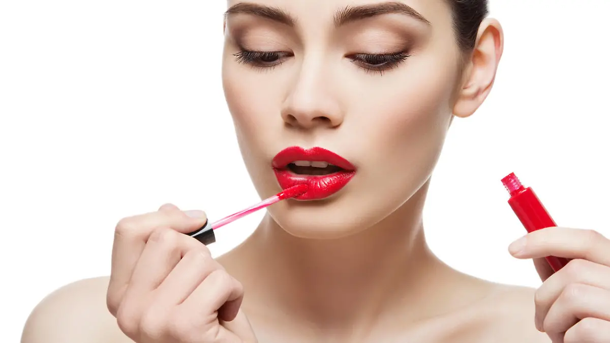 Beautiful young woman applying red lipgloss with applicator. Isolated over white background. Copy space.