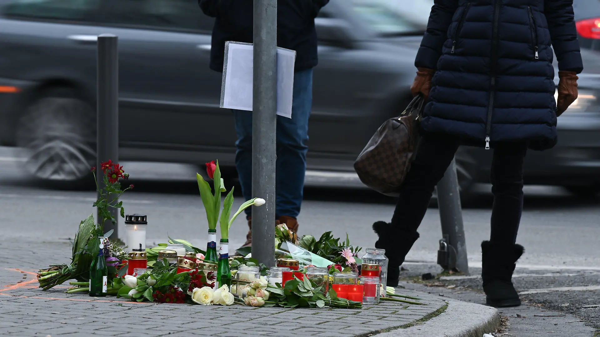 15.02.2021, Hessen, Frankfurt/Main: Menschen trauern an einer Straßenkreuzung im Frankfurter Stadtteil Sachsenhausen, an der Blumen und Kerzen an die Opfer eines tödlichen Verkehrsunfalls vom vergangenen Samstag erinnern. Nach bisherigen Ermittlungen der Polizei waren zwei Fußgänger von einem Pkw erfasst worden, da der Fahrer mit deutlich überhöhter Geschwindigkeit unterwegs war. Foto: Arne Dedert/dpa +++ dpa-Bildfunk +++