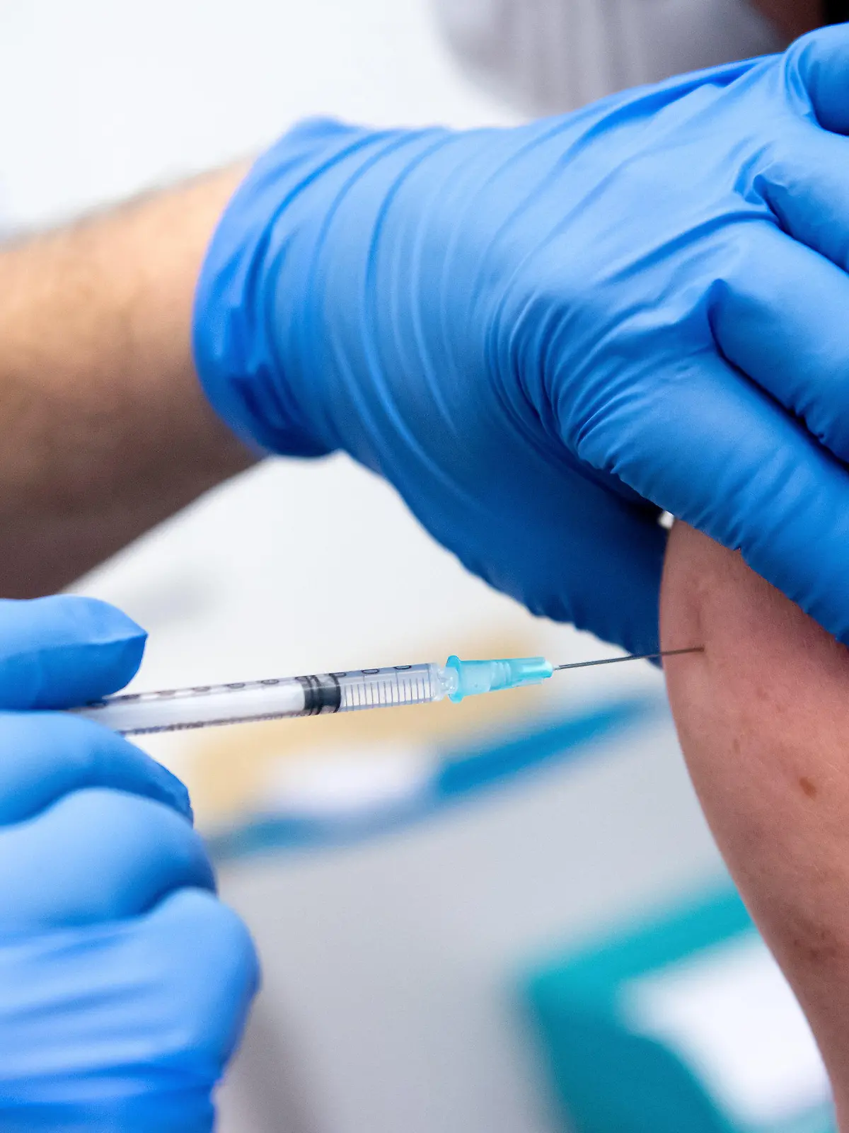ARCHIV - 30.12.2020, Bayern, Gauting: Ein Mitarbeiter der Asklepios Klinik wird von einem Kollegen mit dem Corona-Impfstoff von Biontech/Pfizer geimpft. (zu dpa «Klinik-Chef: Impfpflicht für Personal bitter - «Politikversagen»») Foto: Sven Hoppe/dpa +++ dpa-Bildfunk +++
