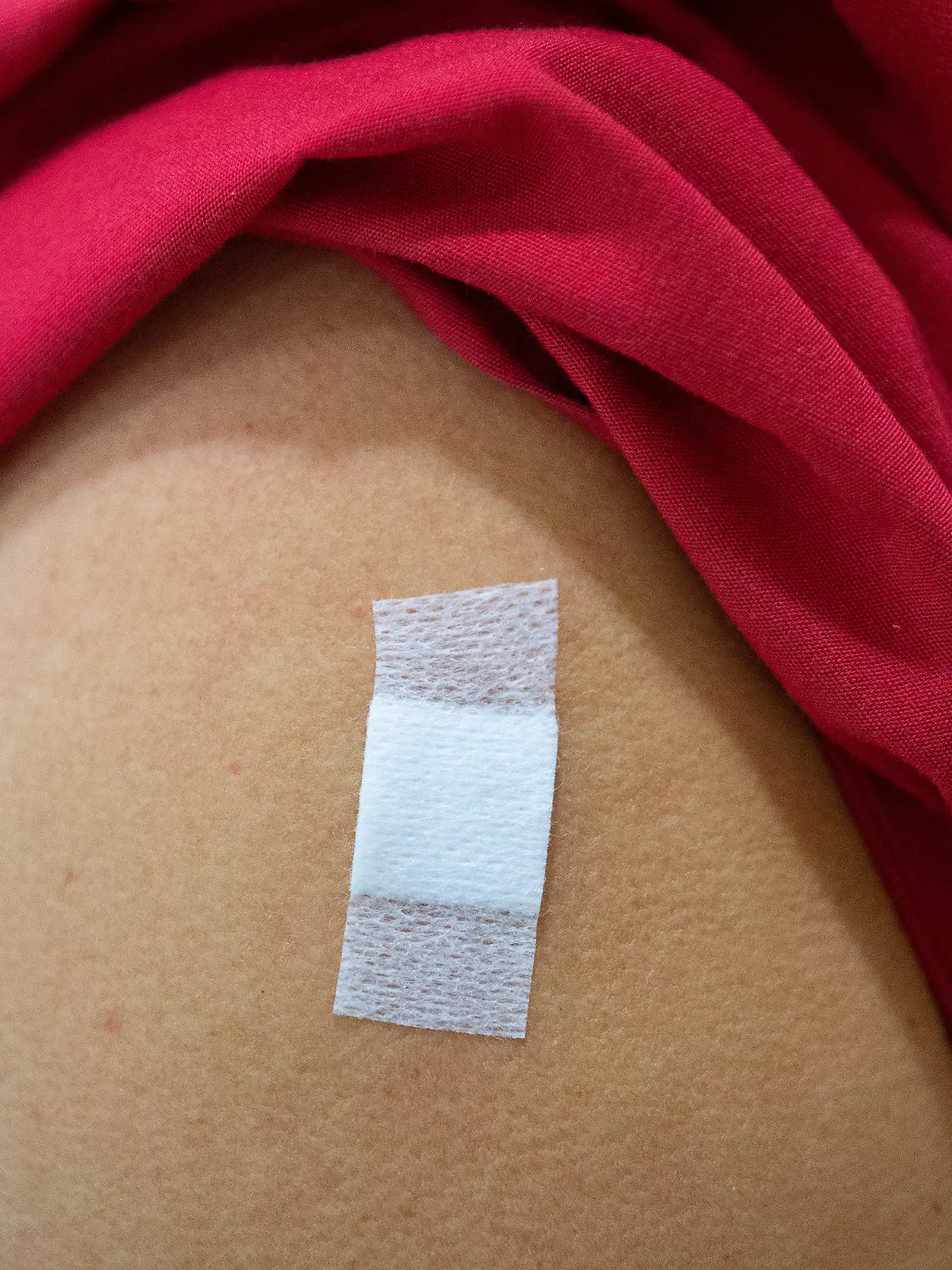ARCHIV - 05.02.2021, Baden-Württemberg, Tübingen: Eine Mitarbeiterin im Alten- und Pflegeheim Bürgerheim hat nach der Corona-Impfung mit dem Impfstoff von Biontech/Pfizer ein Pflaster auf dem Oberarm kleben. Das Pflaster zeigt: Hier wurde gerade jemand gegen das Coronavirus geimpft. (zu dpa: «Baden-Württemberg bereitet sich auf Corona-Impfung von Kindern vor») Foto: Sebastian Gollnow/dpa +++ dpa-Bildfunk +++