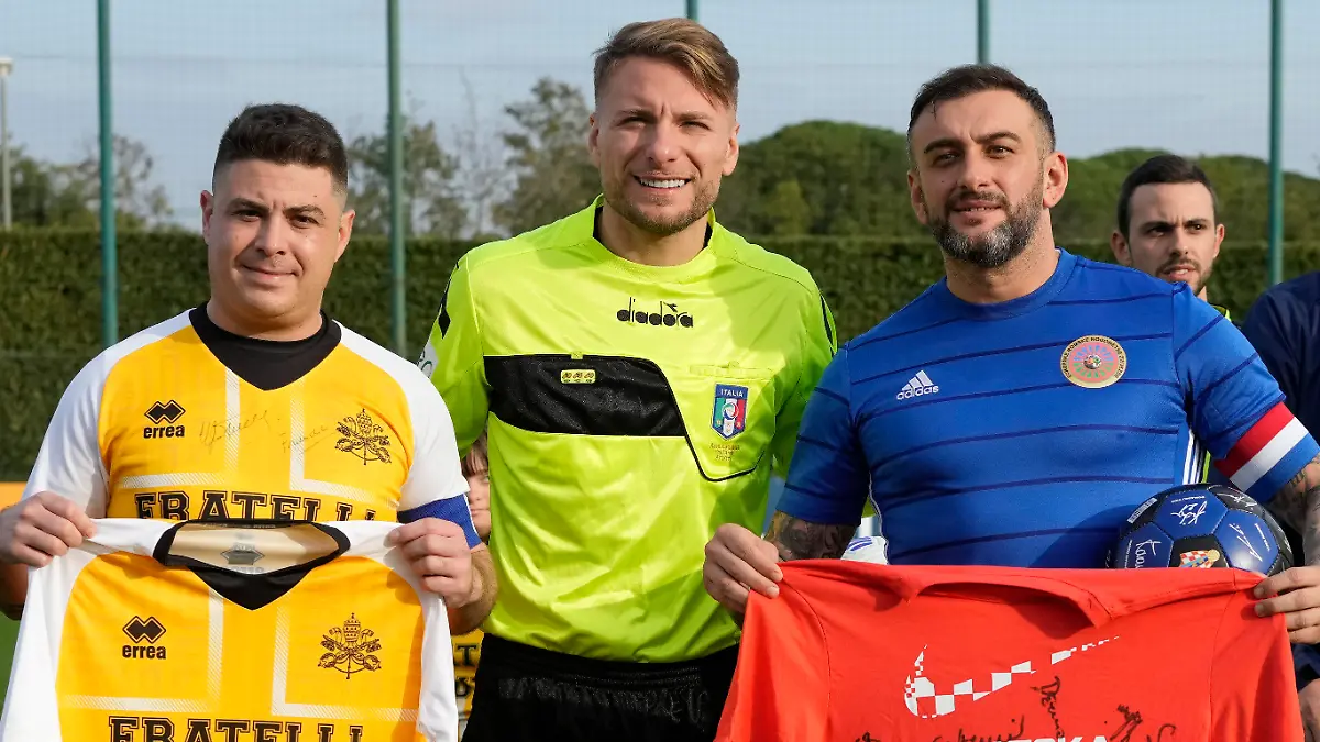 Lazio captain Ciro Immobile, center, poses for a photo with the captains of the Vatican soccer team "Fratelli Tutti" (All Brothers), left, and the World Rom Organization team prior to the start of the "Brothers All" friendly match, at the Italian top league Lazio soccer training facility, in Formello, outskirts of Rome, Sunday, Nov. 21, 2021. The "Brothers All" friendly is an extension of Pope Francis' effort to promote dialogue and fraternity, including through sport, and coincides with Lazio's effort to combat racism and discrimination in soccer. (AP Photo/Andrew Medichini)
