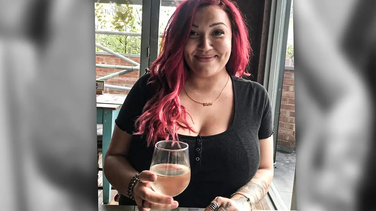 Engländerin Shade sitzt an einem Tisch vor ihr ein Glas Wein.