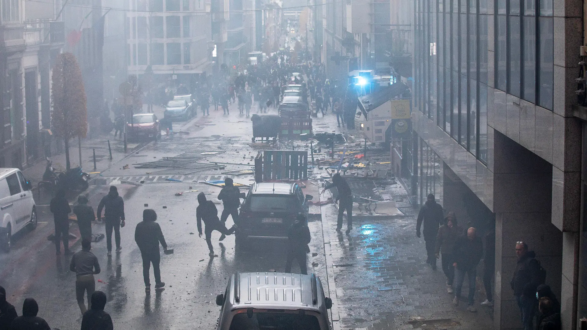 21.11.2021, Belgien, Brüssel: Demonstranten gehen auf einer Straße, auf der Trümmer und Steine liegen. Nach Polizeiangaben sind in Brüssel rund 35.000 Personen auf die Straße gegangen, um gegen die Coronamaßnahmen der Regierung zu demonstrieren. Bei Zusammenstößen musste die Polizei Wasserwerfer und Tränengas einsetzen. Foto: Hatim Kaghat/BELGA/dpa +++ dpa-Bildfunk +++