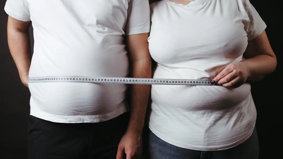 Overweight couple standing together wrapped with measure tape. Dieting, family weight loss and health care