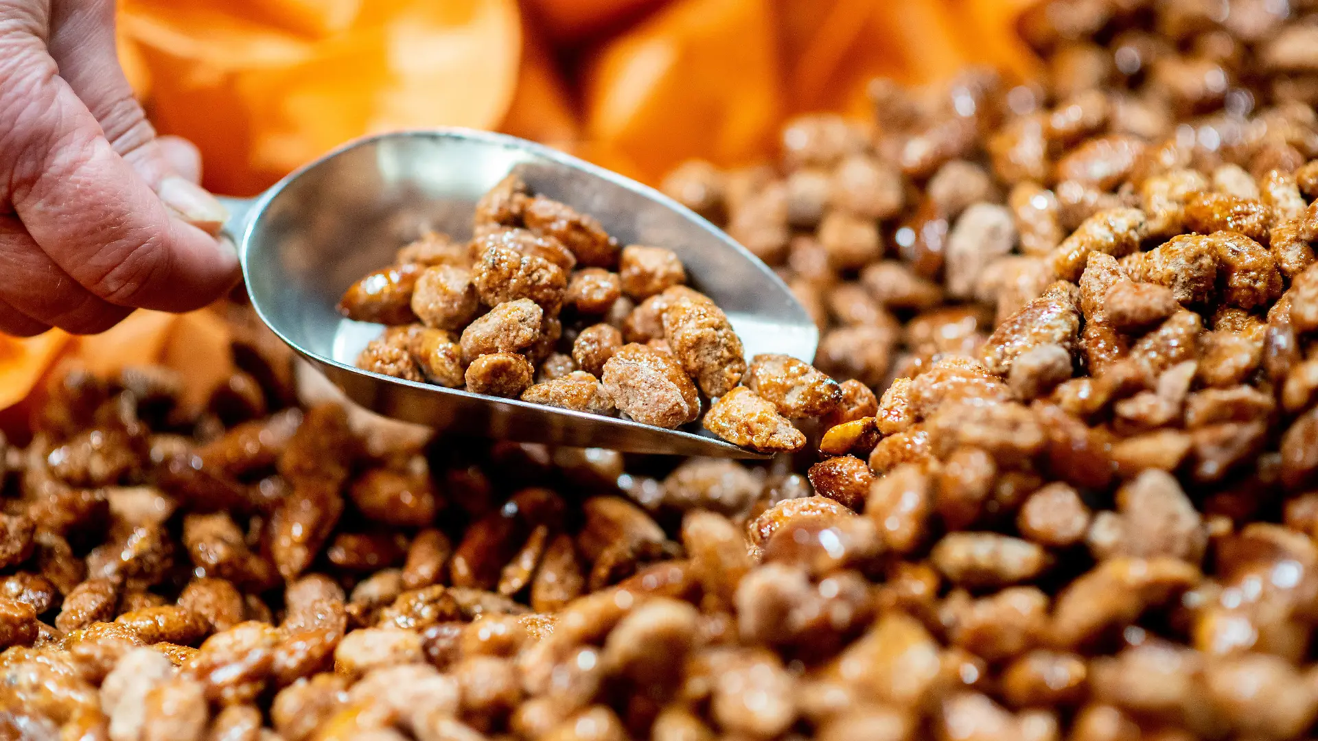16.11.2021, Niedersachsen, Oldenburg: Eine Verkäuferin portioniert gebrannte Mandeln an einem Stand auf dem Lamberti-Markt. Der Weihnachtsmarkt in der Innenstadt wird am 16.11.2021 eröffnet, es gilt eine 3G-Pflicht. Auf dem Oldenburger Lamberti-Markt kommen deshalb Bändchen zum Einsatz, die die Gäste berechtigen, Speisen und Getränke zu kaufen. Foto: Hauke-Christian Dittrich/dpa +++ dpa-Bildfunk +++