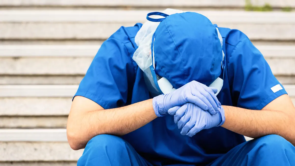Young serious overworked, male mature health care worker sitting looking down very sad