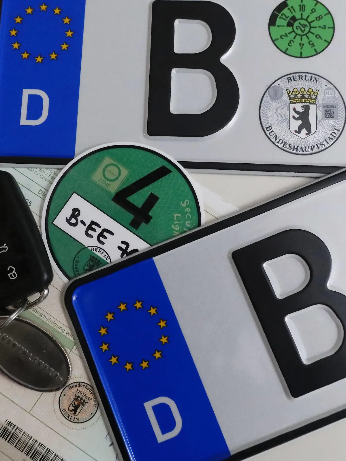 19.01.2023, Berlin, GER - Autokennzeichen, gruene Umweltplakette, Autoschluessel und Zulassungsbescheinigung. Abgasnorm, Anschnitt, Autokennzeichen, Autonummmer, Autoschluessel, Berlin, Besitzernachweise, Buchstaben, Buerokratie, deutsch, Deutschland, Dienstwagen, Dokumente, Draufsicht, Eigentuemernachweise, Eigentum, Eintrag, Europa, europaisch, Fahrzeugpapier, Feinstaubplakette, Halter, Identifikation, Kennzeichen, KFZ-Kennzeichen, KFZ-Papier, KFZ-Zulassung, Legitimation, Lizenz, Neuwagen, Neuzulassung, niemand, Nummernschilder, Papier, Plakette, QF, Querformat, Scheine, Schilder, Schluessel, Stilleben, Stillleben, Studioaufnahme, Symbol, Symbolfoto, Symbolik, symbolisch, TUEV-Plakette, Umweltplakette, Vogelperspektive, Westeuropa, Wirts