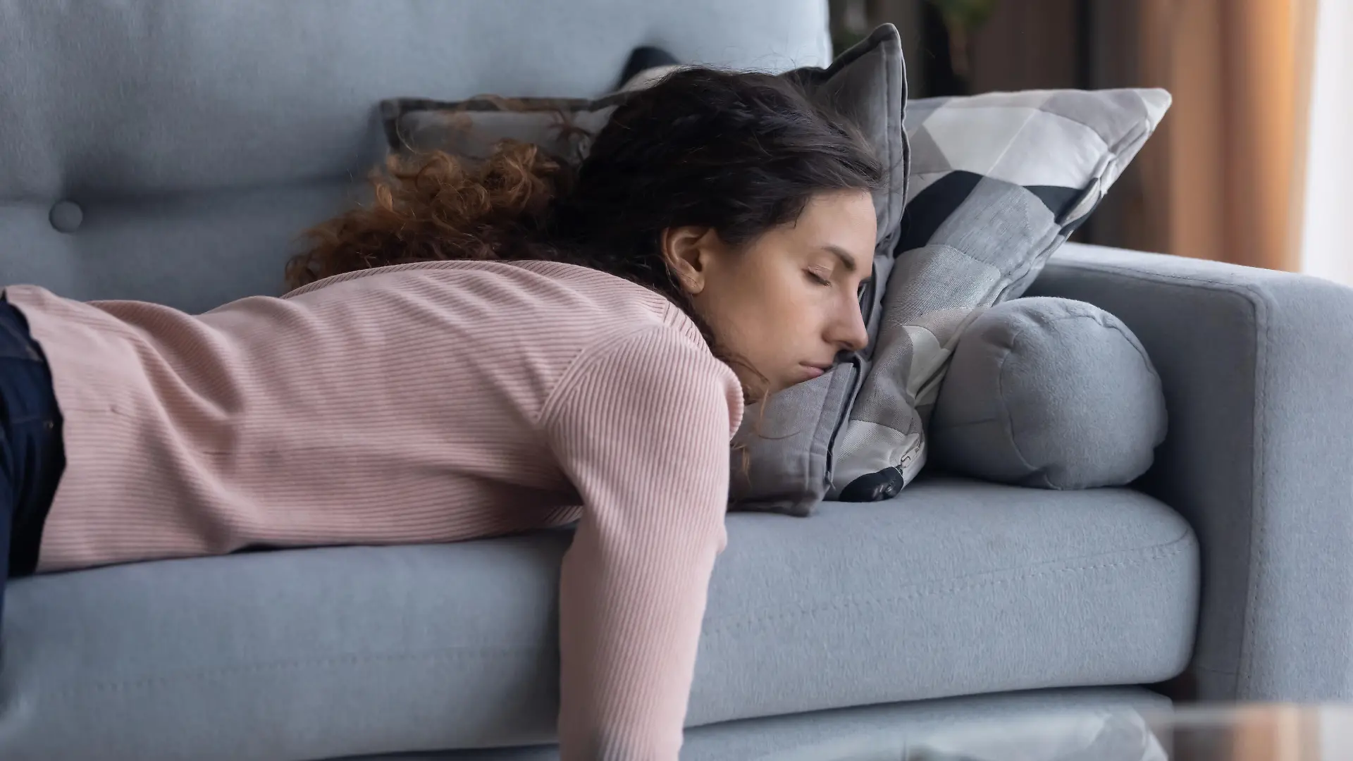 Exhausted young Caucasian woman lying on comfortable sofa in living room sleeping after hard-working day, tired millennial female fall asleep on couch at home, take nap or daydream, fatigue concept