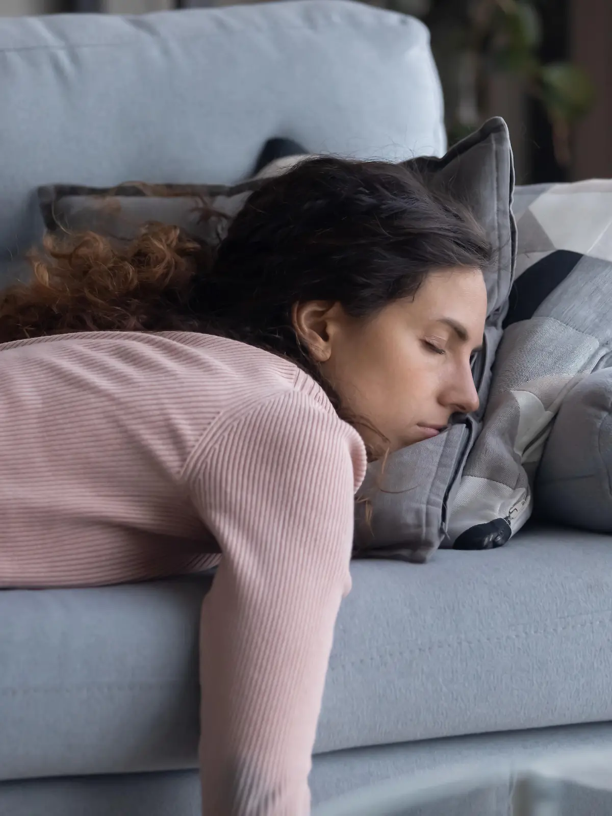 Exhausted young Caucasian woman lying on comfortable sofa in living room sleeping after hard-working day, tired millennial female fall asleep on couch at home, take nap or daydream, fatigue concept