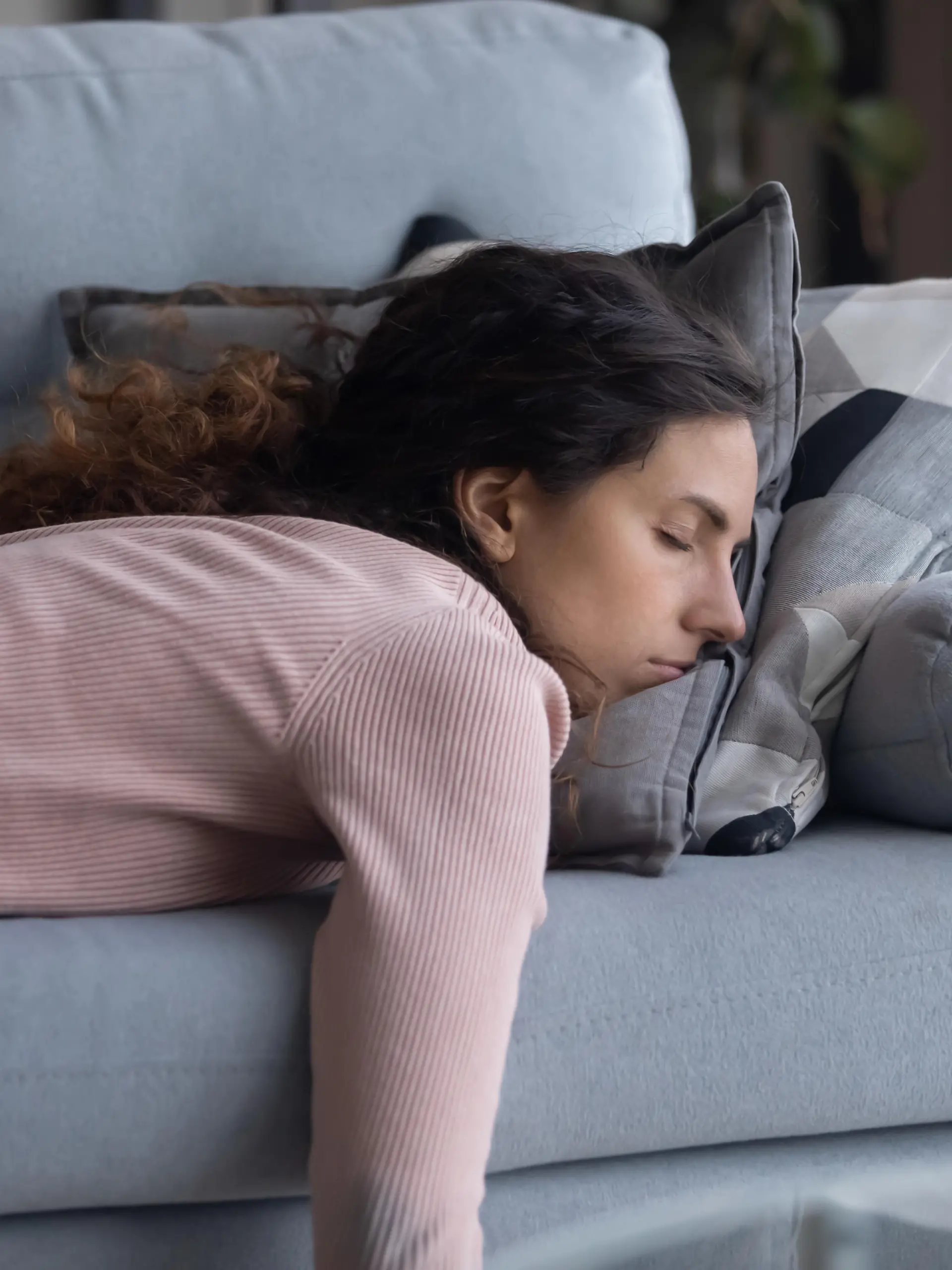 Exhausted young Caucasian woman lying on comfortable sofa in living room sleeping after hard-working day, tired millennial female fall asleep on couch at home, take nap or daydream, fatigue concept