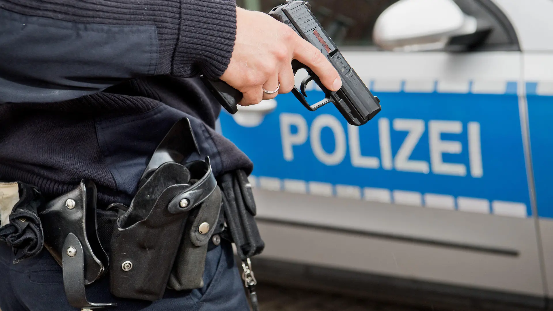 ARCHIV - Ein Polizist posiert am 13.06.2016 für Fotoaufnahmen mit seiner Dienstwaffe HK P2000 9mm vor einem Polizeifahrzeug. Foto: Julian Stratenschulte/dpa (zu dpa «Sachsen rüstet Polizei auf - neue Waffen, neue Ausrüstung» vom 09.08.2016) +++(c) dpa - Bildfunk+++