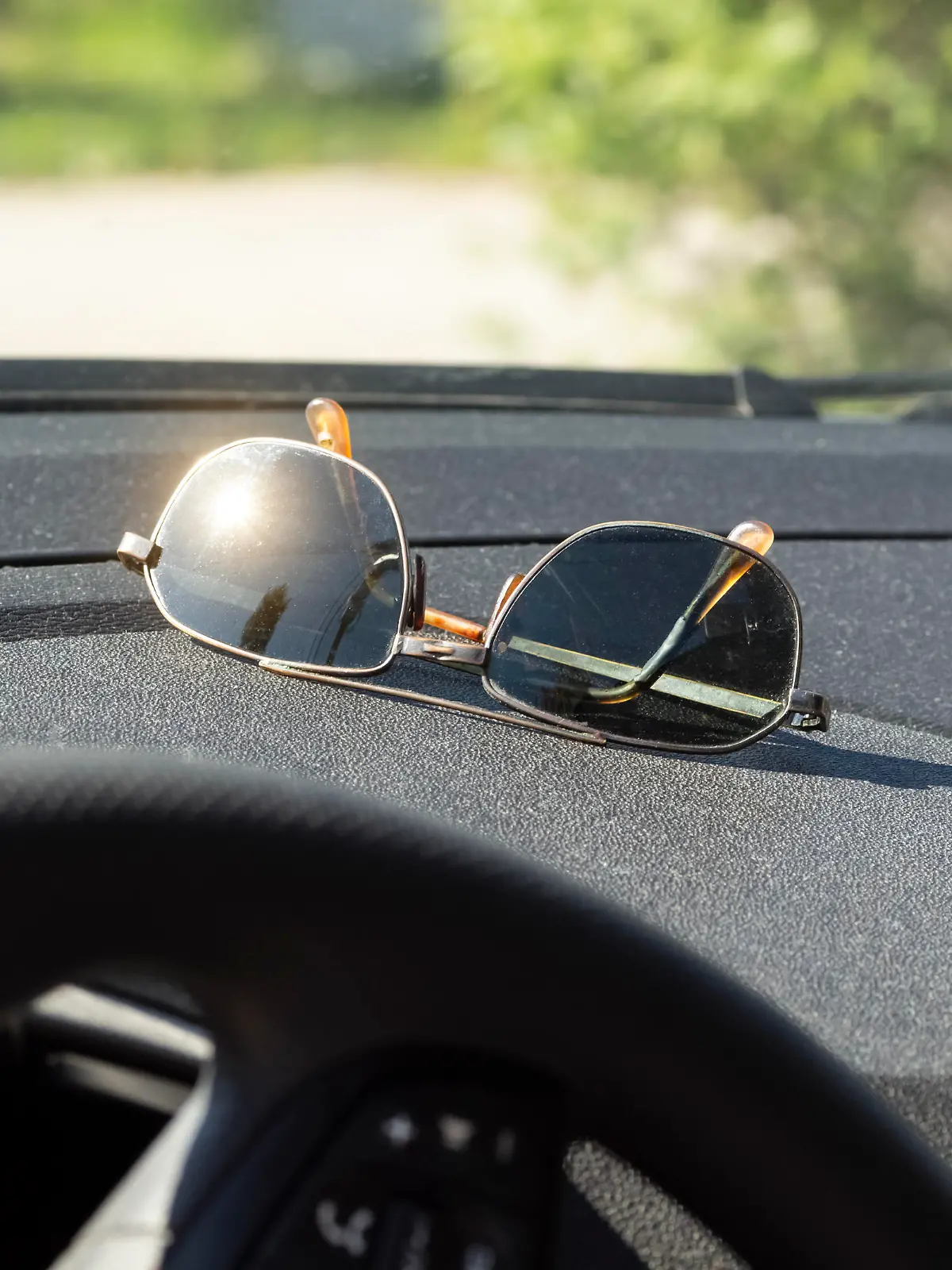 Sunglasses lie on the dashboard of a car while waiting for a ride.