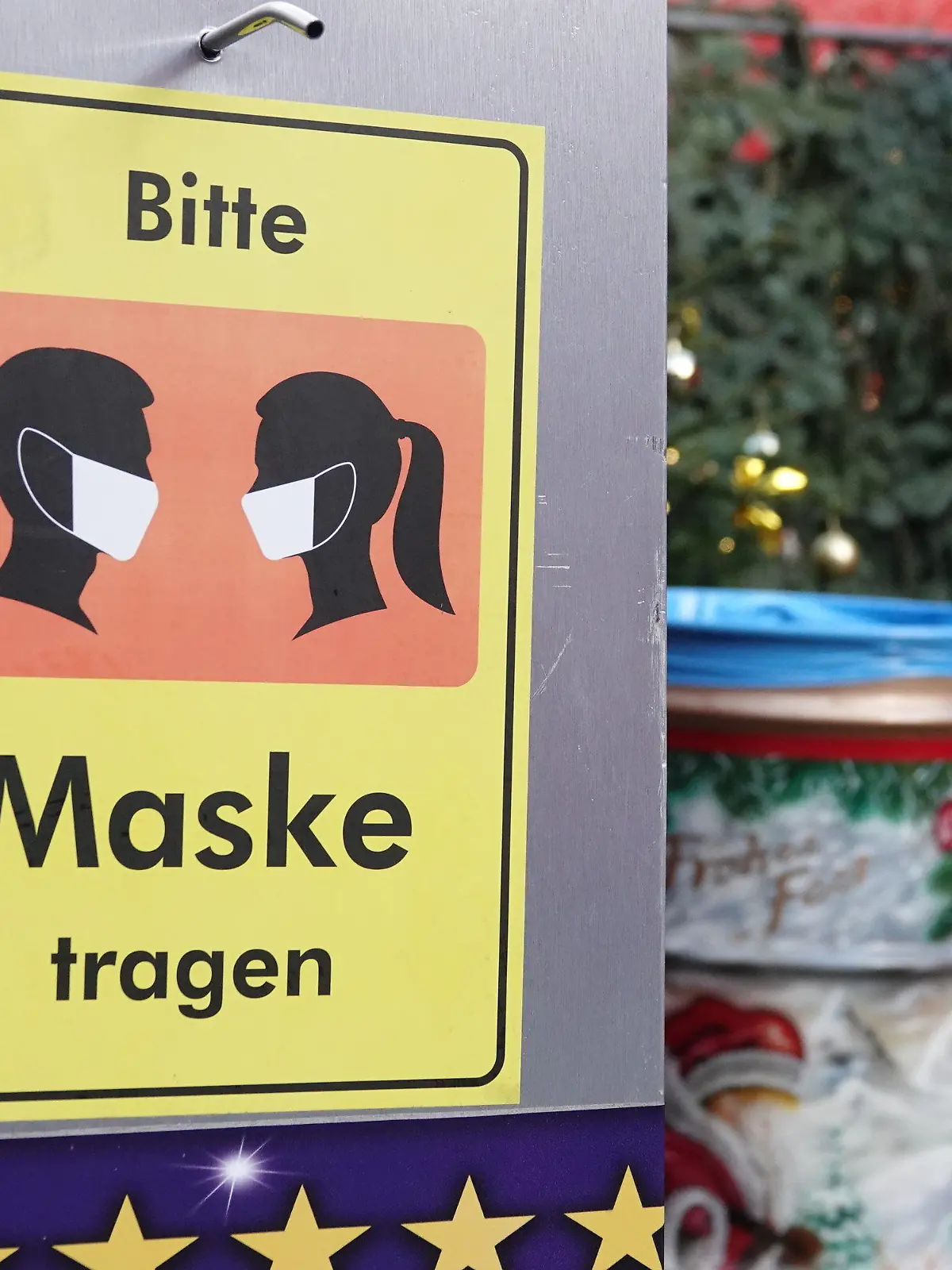 18.11.2021, Nordrhein-Westfalen, Düsseldorf: Auf einem Desinfektionsmittelspender hängt ein Schild mit der Aufschrift «Bitte Maske tragen». Trotz steigender Inzidenzen hat der Weihnachtsmarkt in der Landeshauptstadt am Donnerstag eröffnet. Auf dem Rathausplatz gibt es Einlasskontrollen, rein kommt nur, wer gegen Corona geimpft oder genesen ist. Foto: Mona Wenisch/dpa +++ dpa-Bildfunk +++