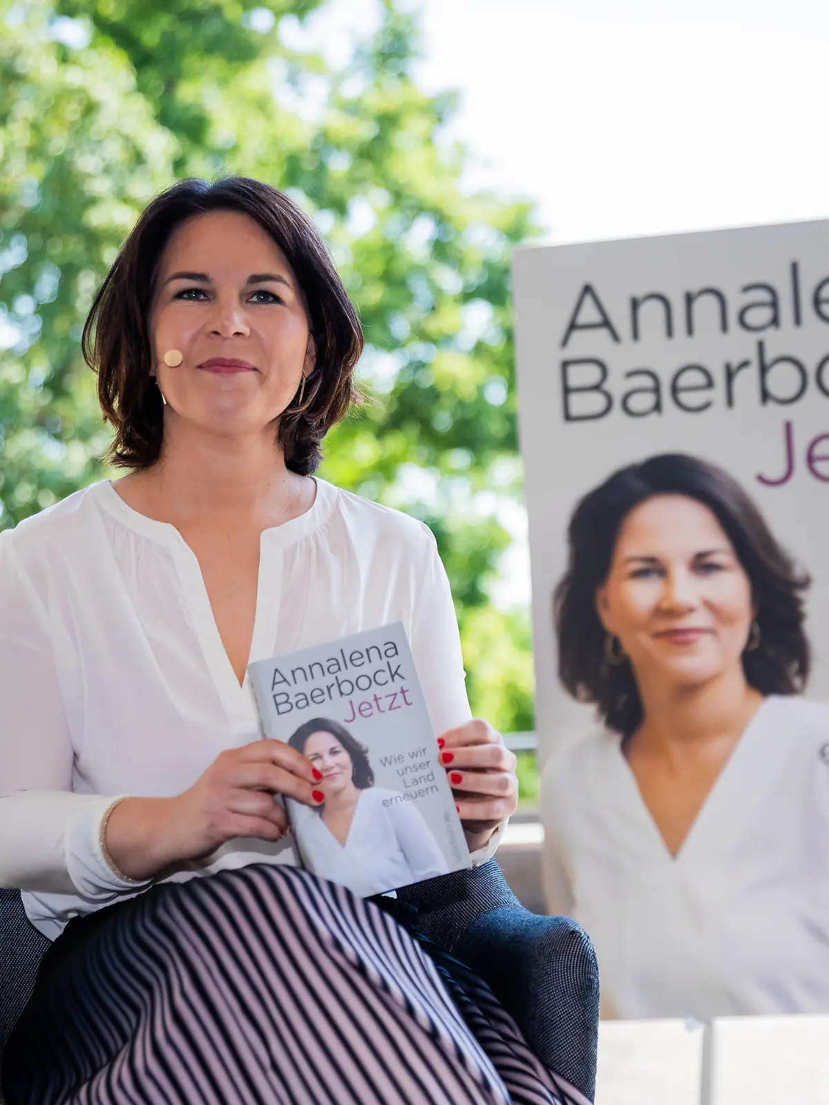 17.06.2021, Berlin: Annalena Baerbock, Kanzlerkandidatin und Bundesvorsitzende von Bündnis 90/Die Grünen, sitzt zu Beginn der Vorstellung ihres Buches «Jetzt. Wie wir unser Land erneuern» mit einem Exemplar in der Hand auf der Bühne. Foto: Christoph Soeder/dpa +++ dpa-Bildfunk +++