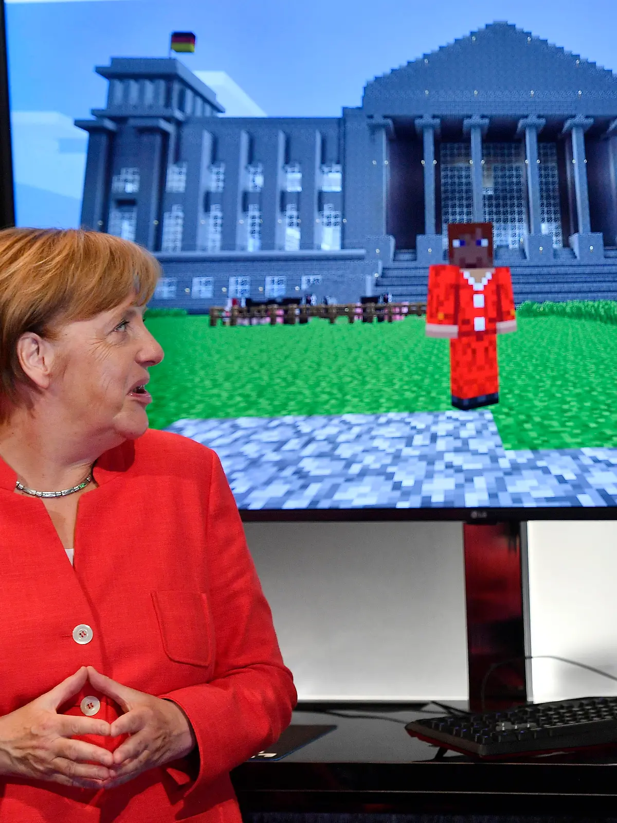 German chancellor Angela Merkel standing beside a Minecraft game, showing her in front of the German Reichstag, during the Gamescom fair for computer games in Cologne, Germany, Tuesday, Aug. 22, 2017. The leading European trade fair for digital gaming culture is the meeting point for global companies from the entertainment industry and the international gaming community. (AP Photo/Martin Meissner)