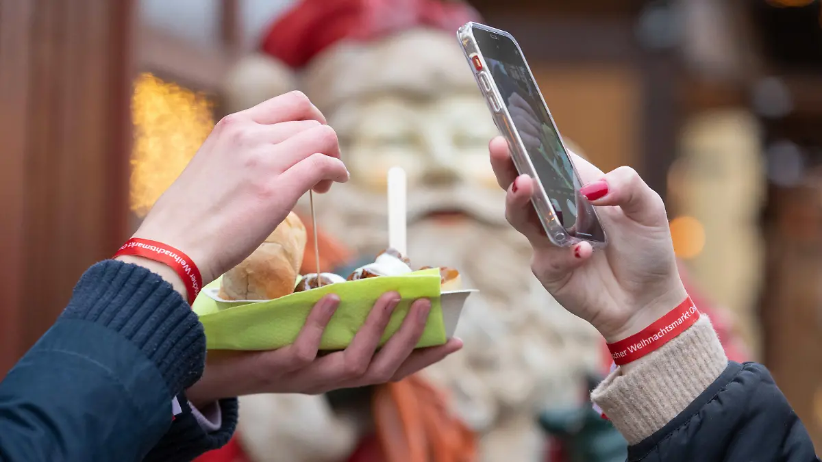 15.11.2021, Niedersachsen, Osnabrück: Weihnachtsmarkt-Besucher tragen spezielle Bändchen. Für den Weihnachtsmarkt gilt eine 2G-Pflicht. Auf dem Osnabrücker Weihnachtsmarkt kommen deshalb Bändchen zum Einsatz, die die Gäste berechtigen, Speisen und Getränke zu kaufen. Dazu muß vorher nachgewiesen werden, ob man vollständig geimpft oder genesen ist. Foto: Friso Gentsch/dpa +++ dpa-Bildfunk +++