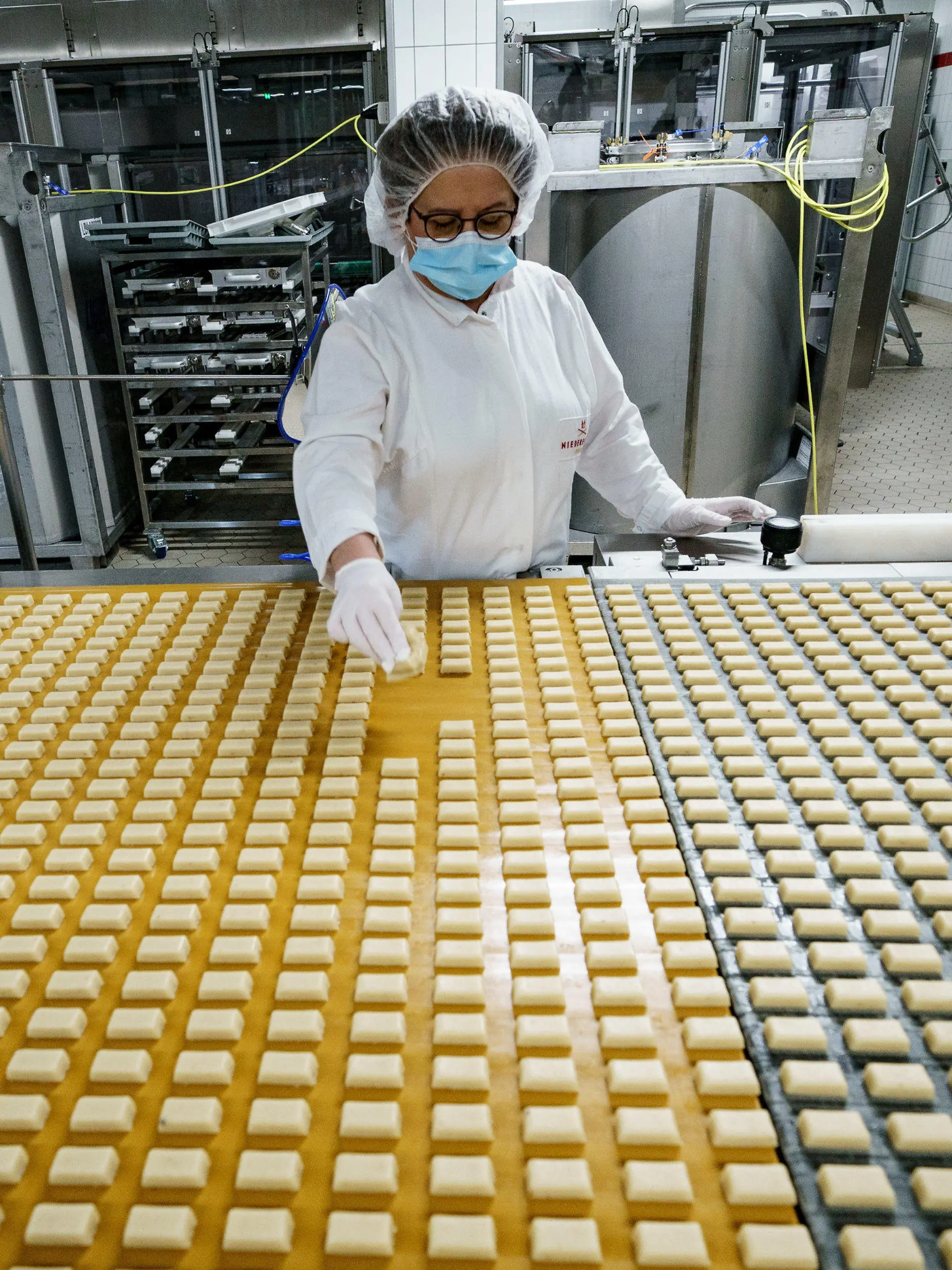 03.11.2021, Schleswig-Holstein, Lübeck: Eine Arbeiterin kontrolliert in einer Produktionsanlage der Firma Niederegger die Form von Marzipanstücken. Bei Niederegger ist die Weihnachtsproduktion in vollem Gang. Foto: Axel Heimken/dpa +++ dpa-Bildfunk +++