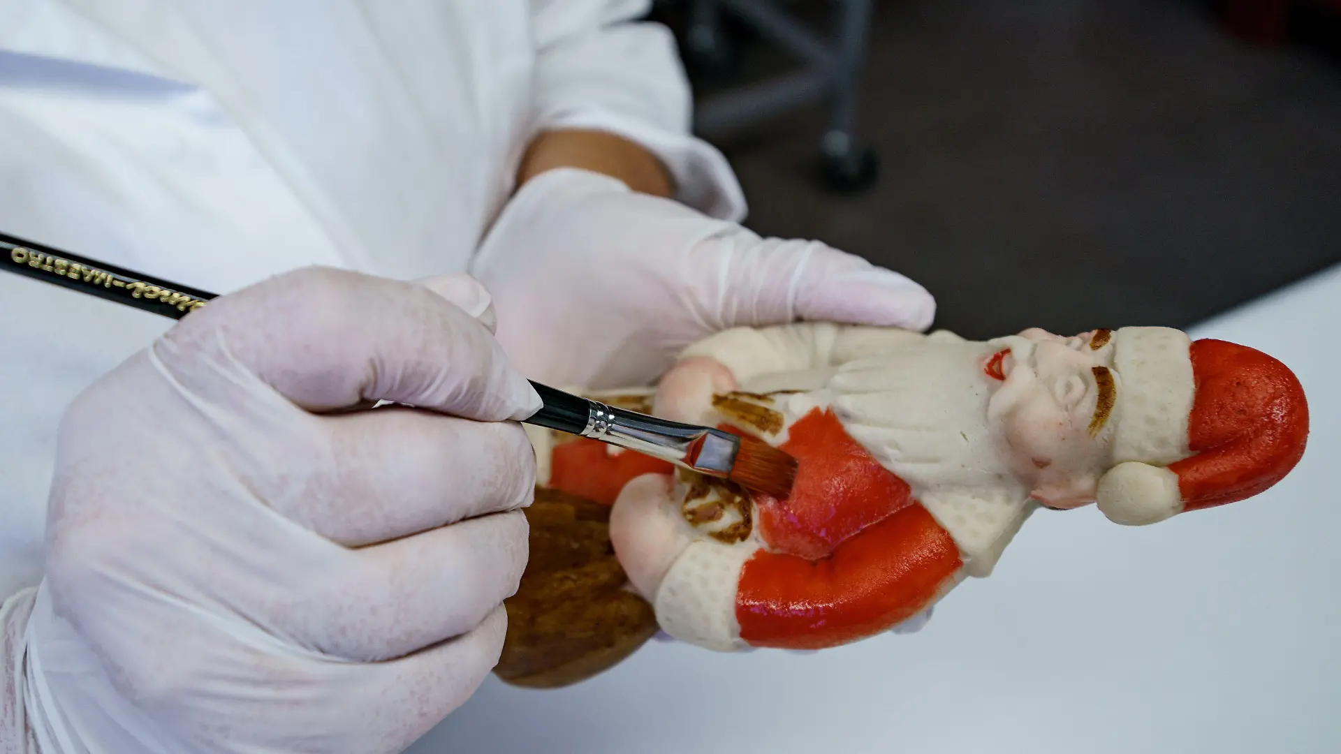 03.11.2021, Schleswig-Holstein, Lübeck: Eine Arbeiterin bemalt in einer Produktionshalle der Firma Niederegger einen Weihnachtsmann aus Marzipan mit Lebensmittelfarbe. Bei Niederegger ist die Weihnachtsproduktion in vollem Gang. Foto: Axel Heimken/dpa +++ dpa-Bildfunk +++
