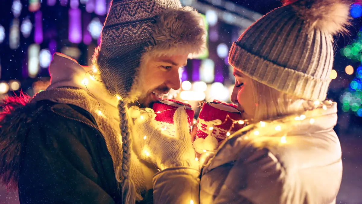 Adult couple hanging out in the city during Christmas time over lights city background and snow at night