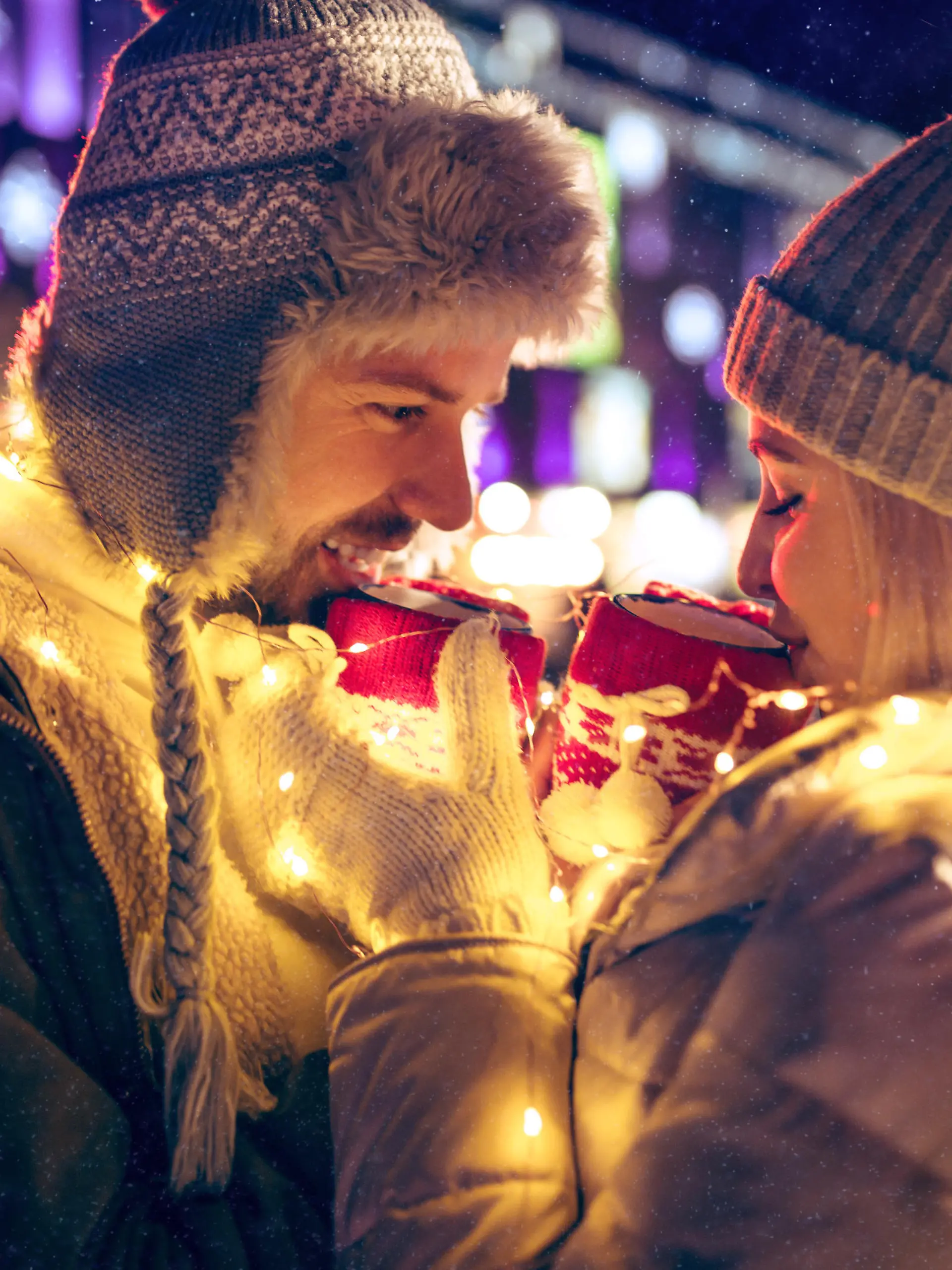 Adult couple hanging out in the city during Christmas time over lights city background and snow at night