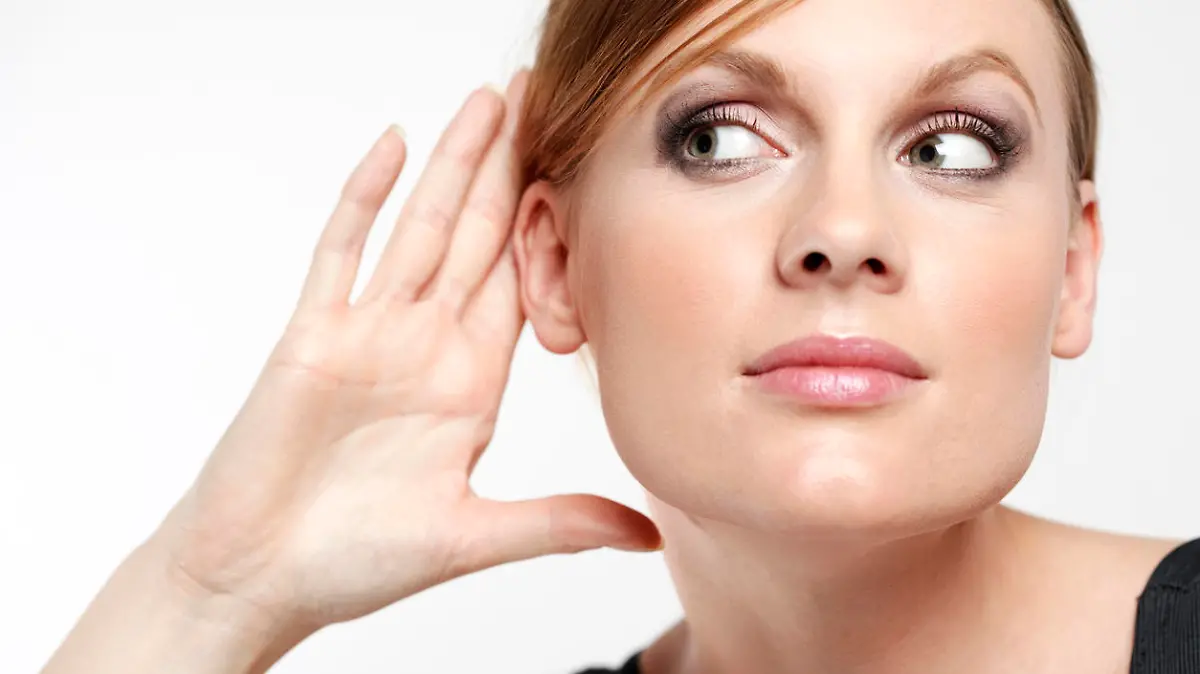 Young woman with cupping hand behind ear and eavesdropping