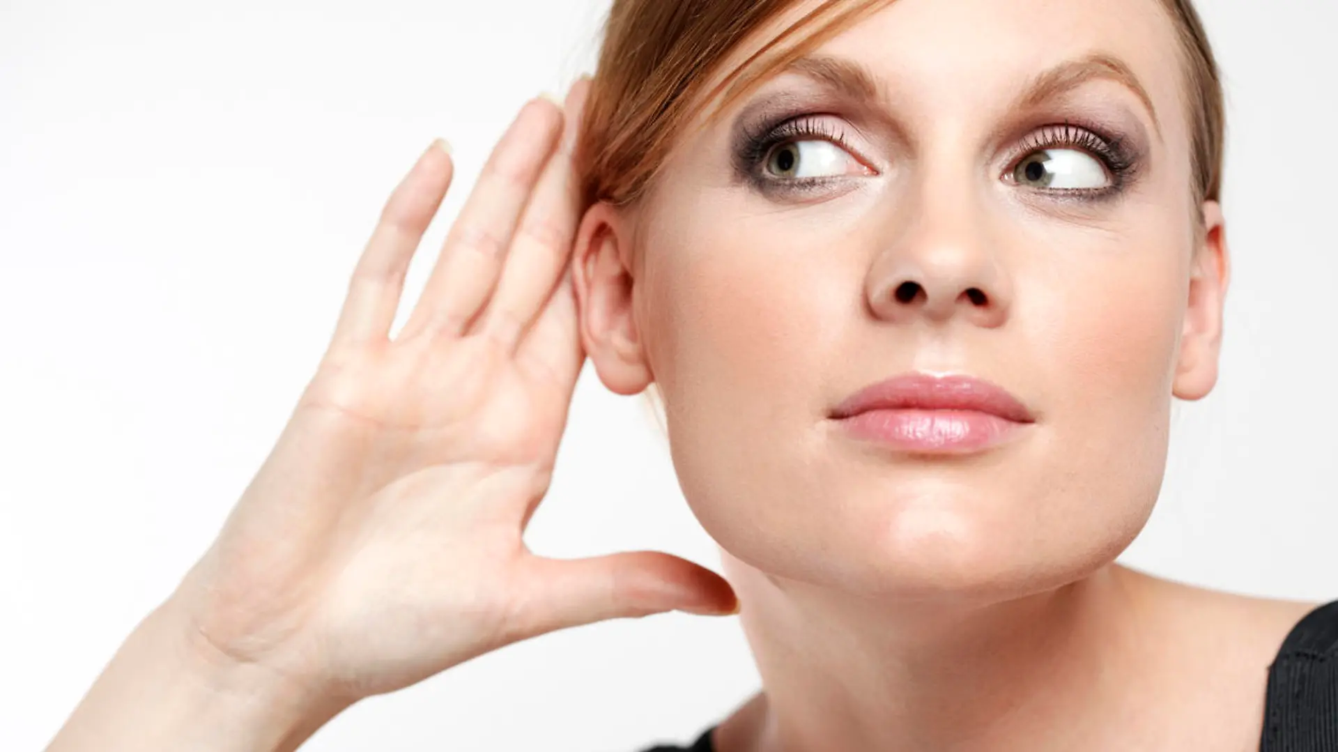 Young woman with cupping hand behind ear and eavesdropping