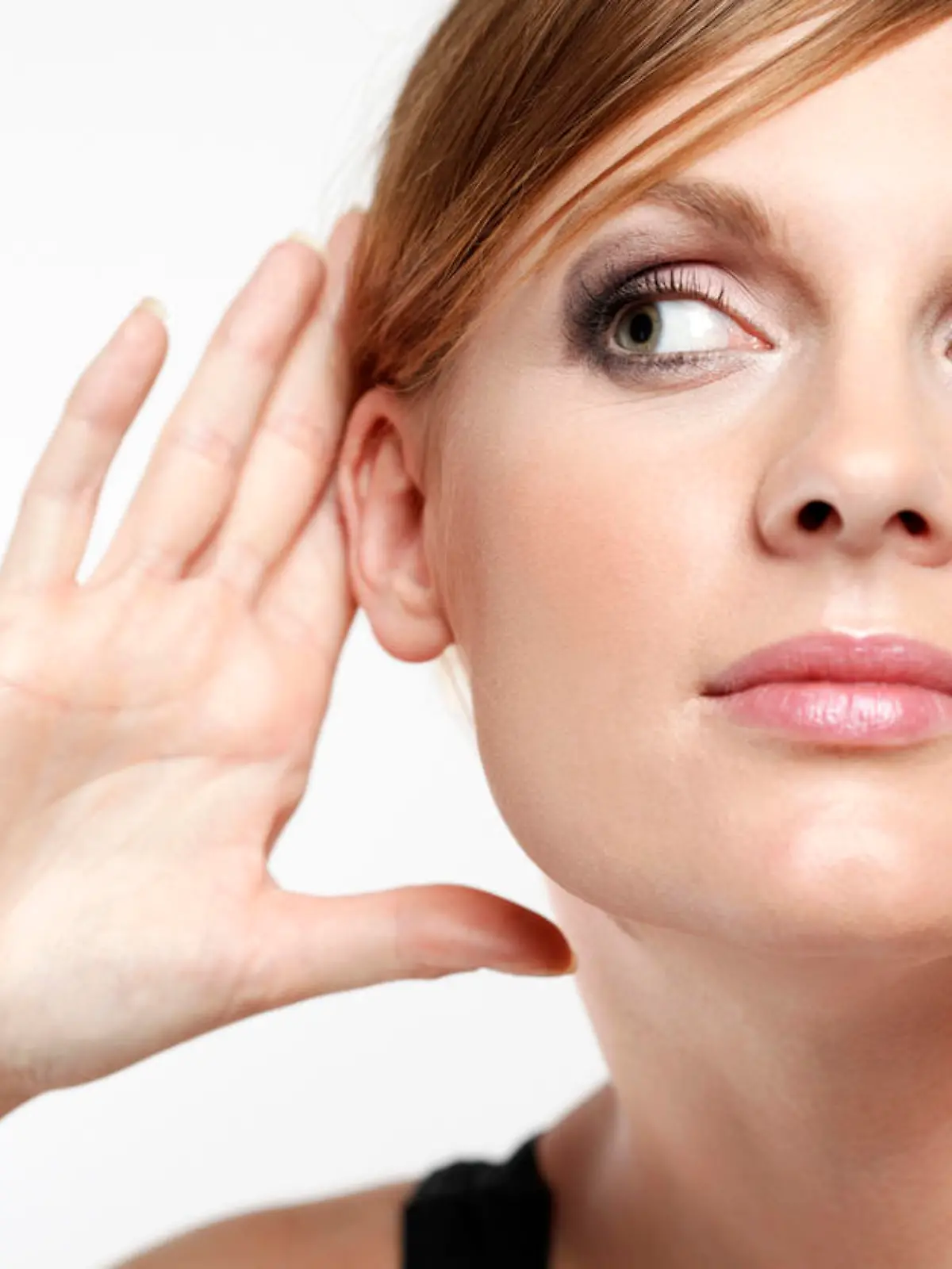 Young woman with cupping hand behind ear and eavesdropping