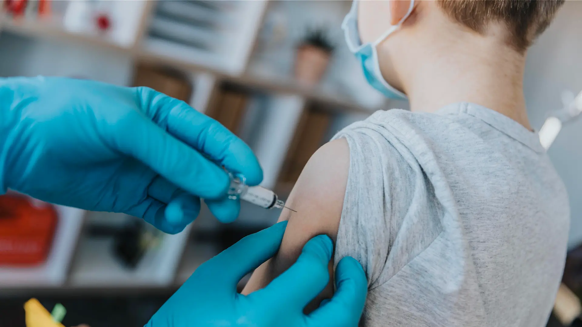 Doctor wearing protective glove injecting COVID-19 vaccine in boy arm at clinic model released Symbolfoto property released MFF07478 