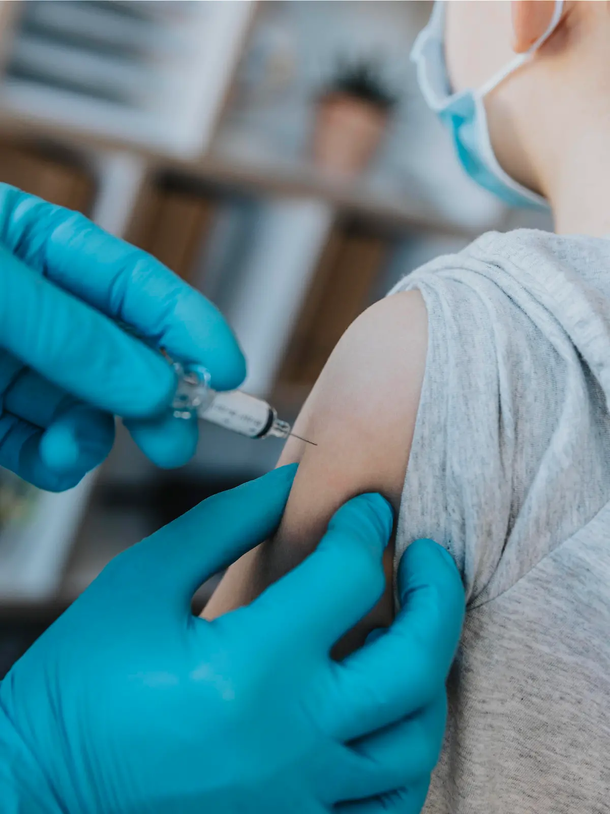 Doctor wearing protective glove injecting COVID-19 vaccine in boy arm at clinic model released Symbolfoto property released MFF07478 