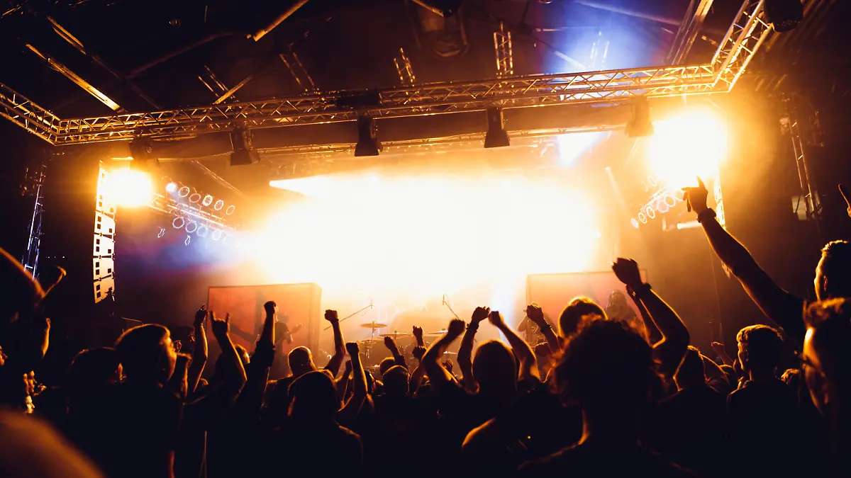 Colorful crowd of uncrecognized people of a big music festival or concert in a stage lights as a beautiful background