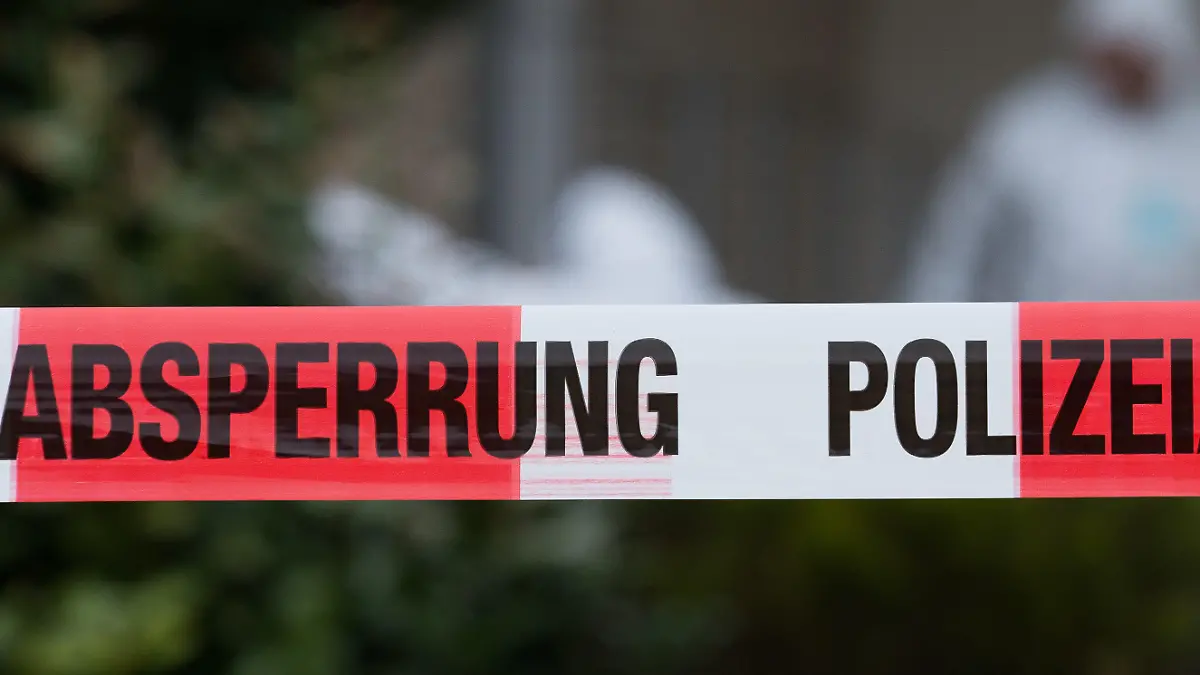 13.04.2018, Niedersachsen, Osnabrück: Beamte der Spurensicherung untersuchen den Eingang eines Hauses. Im Vordergrund eine Polizeiabsperrung. In der Garage hatte die Polizei eine zerstückelte Frauenleiche entdeckt. Unter dringendem Tatverdacht stehe der Sohn des 61 Jahre alten Opfers, so die Polizei. Eine Zeugin hatte die Frau am Mittwoch als vermisst gemeldet, nachdem diese seit Tagen nicht bei der Arbeit erschienen war. Foto: Friso Gentsch/dpa +++ dpa-Bildfunk +++
