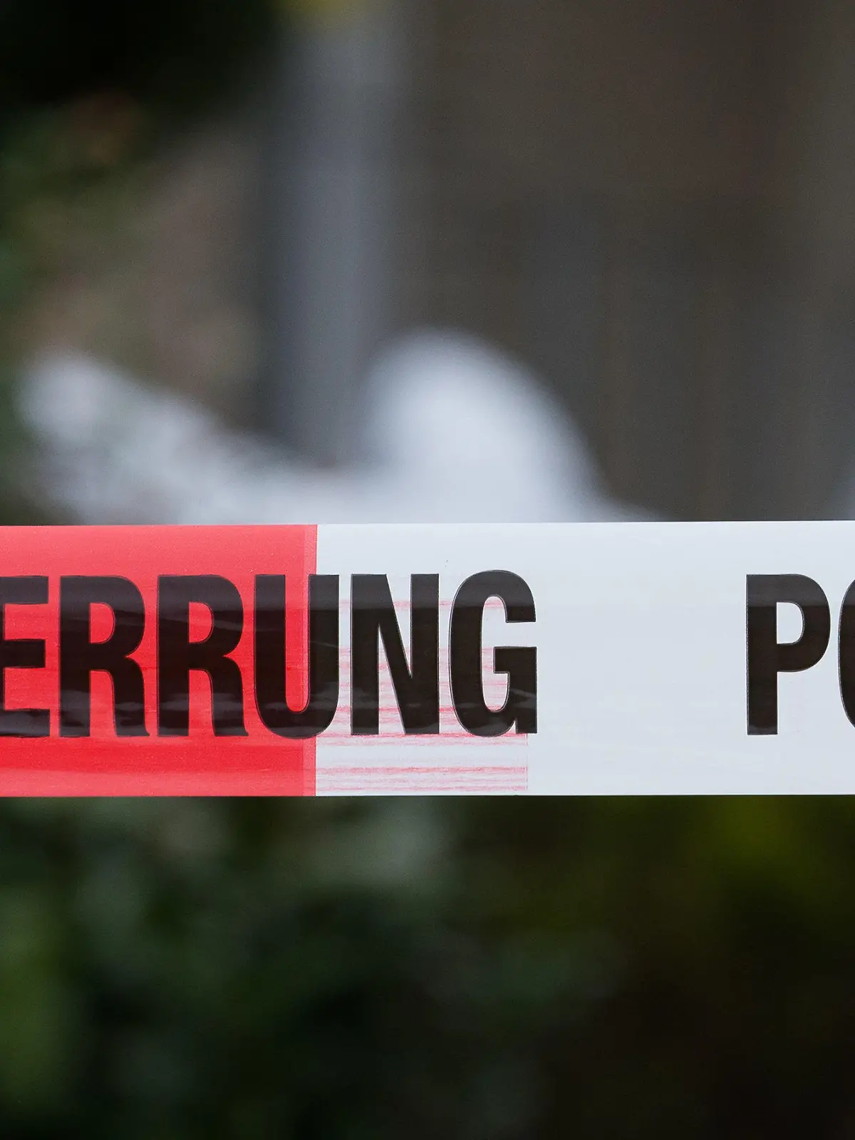 13.04.2018, Niedersachsen, Osnabrück: Beamte der Spurensicherung untersuchen den Eingang eines Hauses. Im Vordergrund eine Polizeiabsperrung. In der Garage hatte die Polizei eine zerstückelte Frauenleiche entdeckt. Unter dringendem Tatverdacht stehe der Sohn des 61 Jahre alten Opfers, so die Polizei. Eine Zeugin hatte die Frau am Mittwoch als vermisst gemeldet, nachdem diese seit Tagen nicht bei der Arbeit erschienen war. Foto: Friso Gentsch/dpa +++ dpa-Bildfunk +++