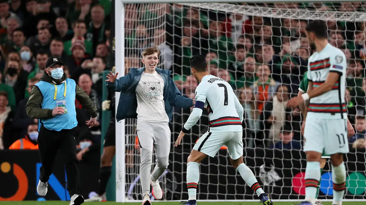 Republic of Ireland v Portugal - FIFA World Cup 2022 - European Qualifying - Group A - Aviva Stadium. A pitch invader approaches Portugal's Cristiano Ronaldo during the FIFA World Cup Qualifying match at the Aviva Stadium, Dublin. Picture date: Thursday November 11, 2021. See PA Story SOCCER Republic. Photo credit should read: Brian Lawless/PA Wire RESTRICTIONS: Use subject to restrictions. Editorial use only, no commercial use without prior consent from rights holder. URN:63674365