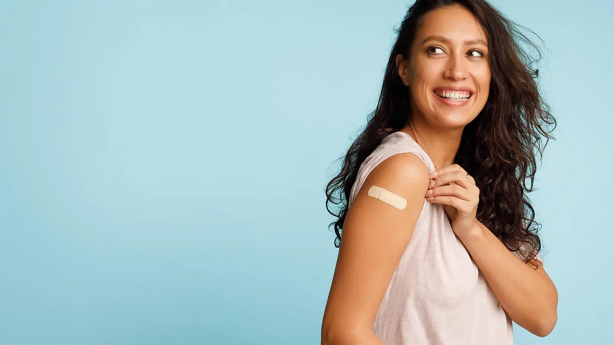 Vaccination Saves Lives. Joyful Arab Woman Showing Vaccinated Arm With Medical Bandage After Coronavirus Antiviral Vaccine Injection Posing On Blue Background. Stop Coronavirus. Panorama, Copy Space