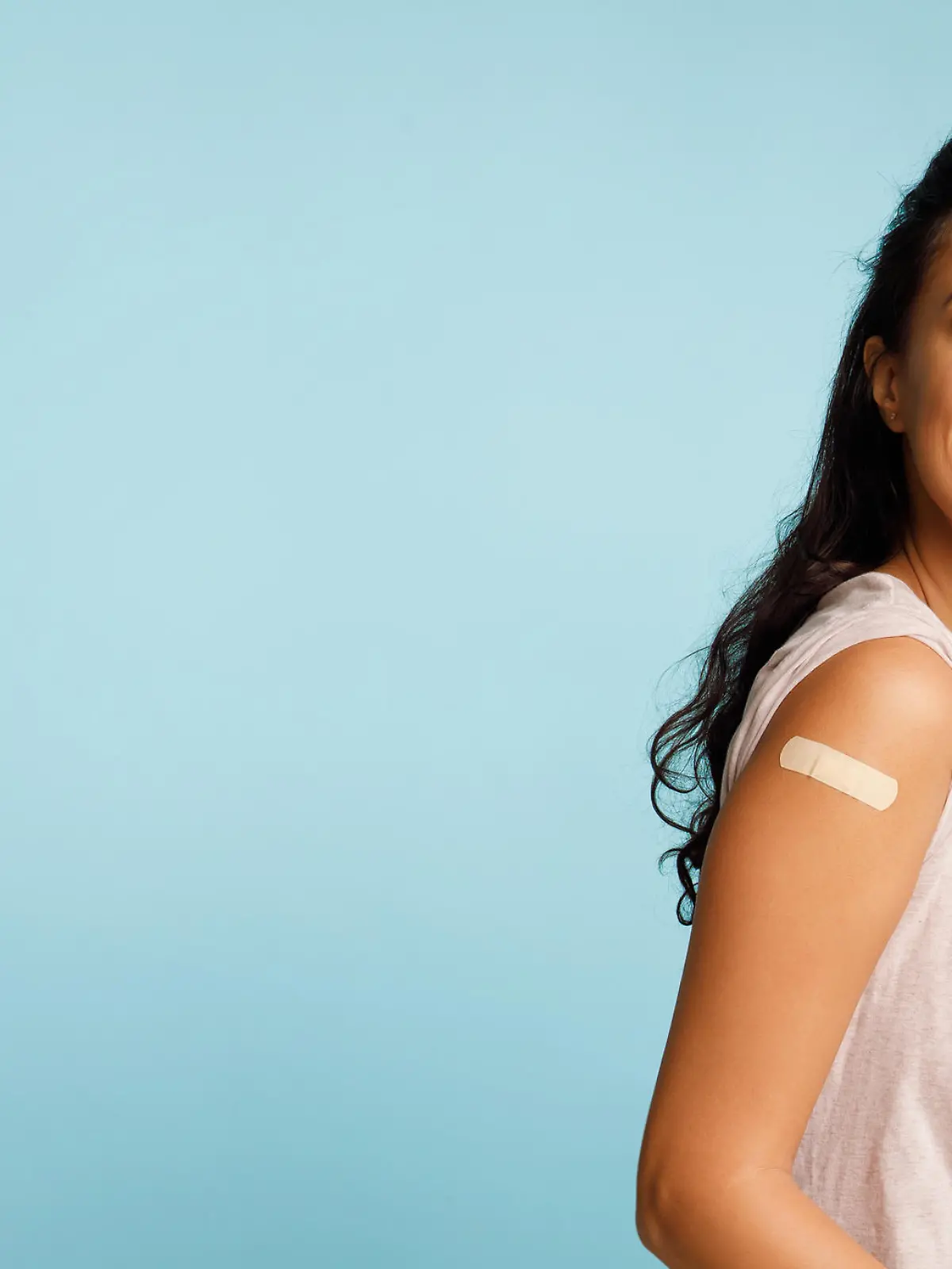 Vaccination Saves Lives. Joyful Arab Woman Showing Vaccinated Arm With Medical Bandage After Coronavirus Antiviral Vaccine Injection Posing On Blue Background. Stop Coronavirus. Panorama, Copy Space