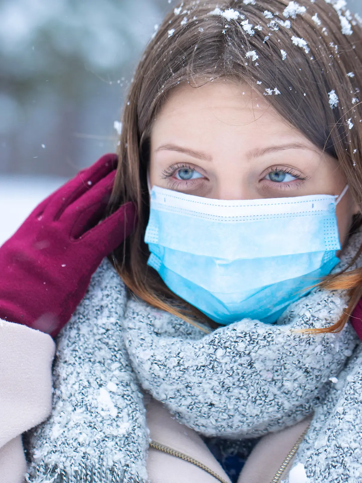 Young woman blue eyed girl posing on the snow with protective mask