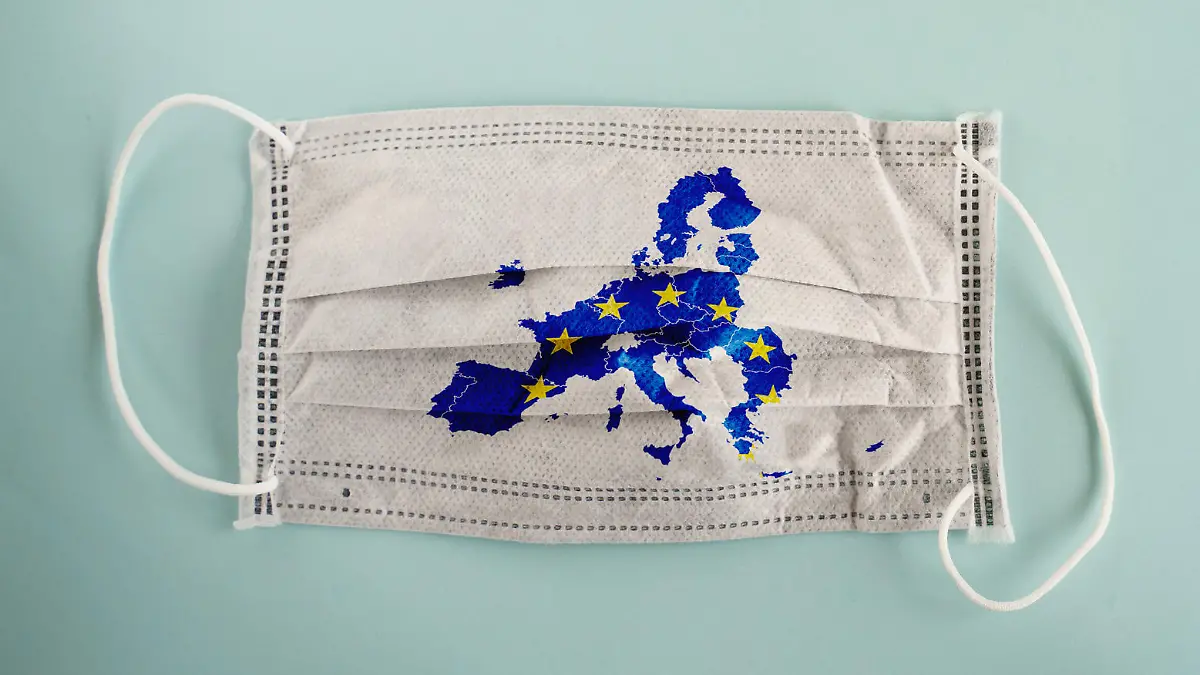White medical mask with coronavirus word and European Union map on it isolated on cyan background. Face mask protection against pollution, virus, flu and coronavirus. Health care and surgical concept.
