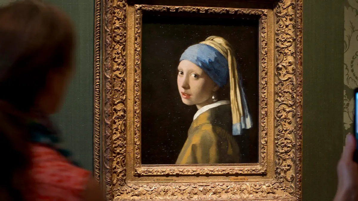 Visitors take pictures of Johannes Vermeer's Girl with a Pearl Earring (approx. 1665) during a preview for the press of the renovated Mauritshuis in The Hague, Netherlands, Friday, June 20, 2014. The Mauritshuis will open its doors to the public for free from 8 pm till midnight on Friday June 27th after the official ceremonial opening. From June 28 onwards the museum will revert to regular opening hours. (AP Photo/Peter Dejong)