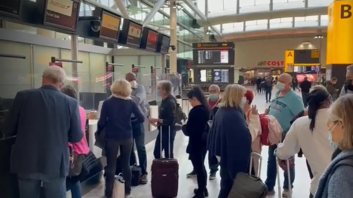 Urlauber stehen am Flughafen in einer Reihe.