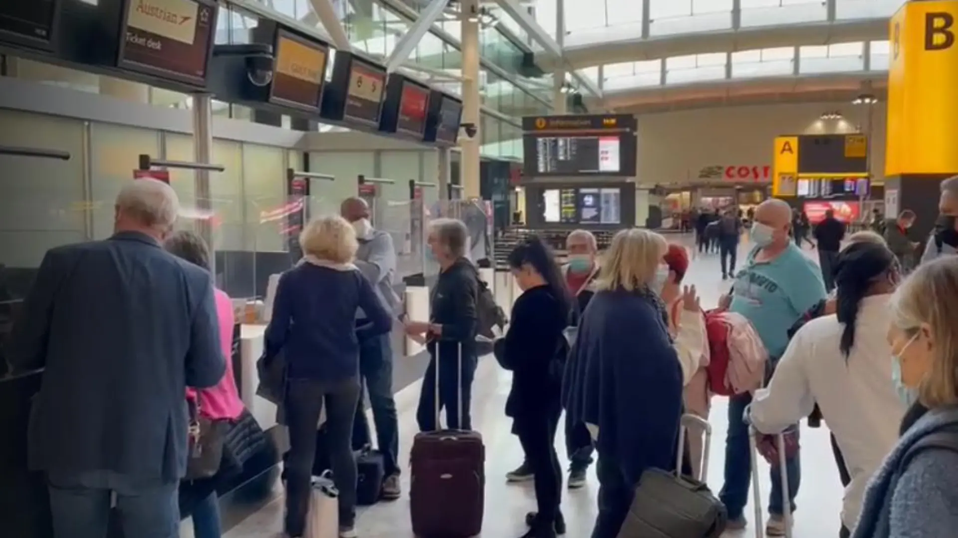 Urlauber stehen am Flughafen in einer Reihe.
