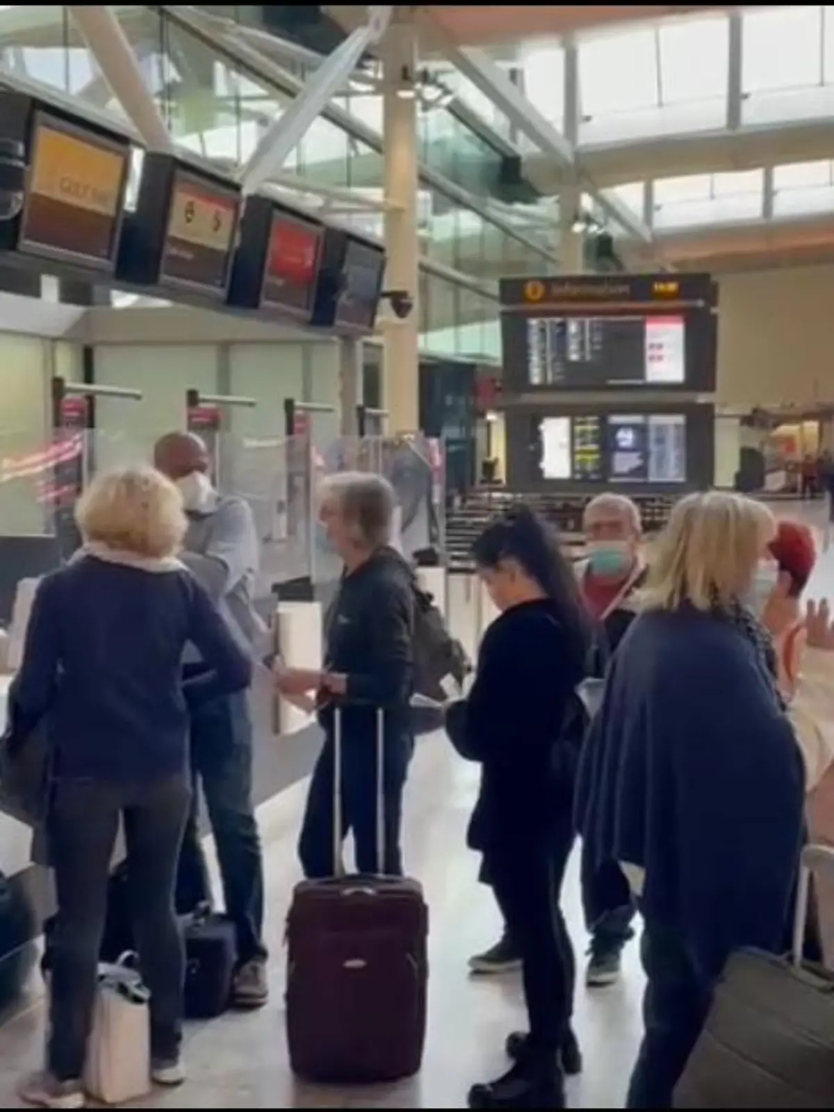Urlauber stehen am Flughafen in einer Reihe.