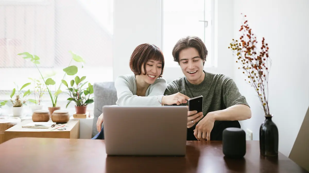 Couple sitting behind a coffee table, installing virtual assistant.