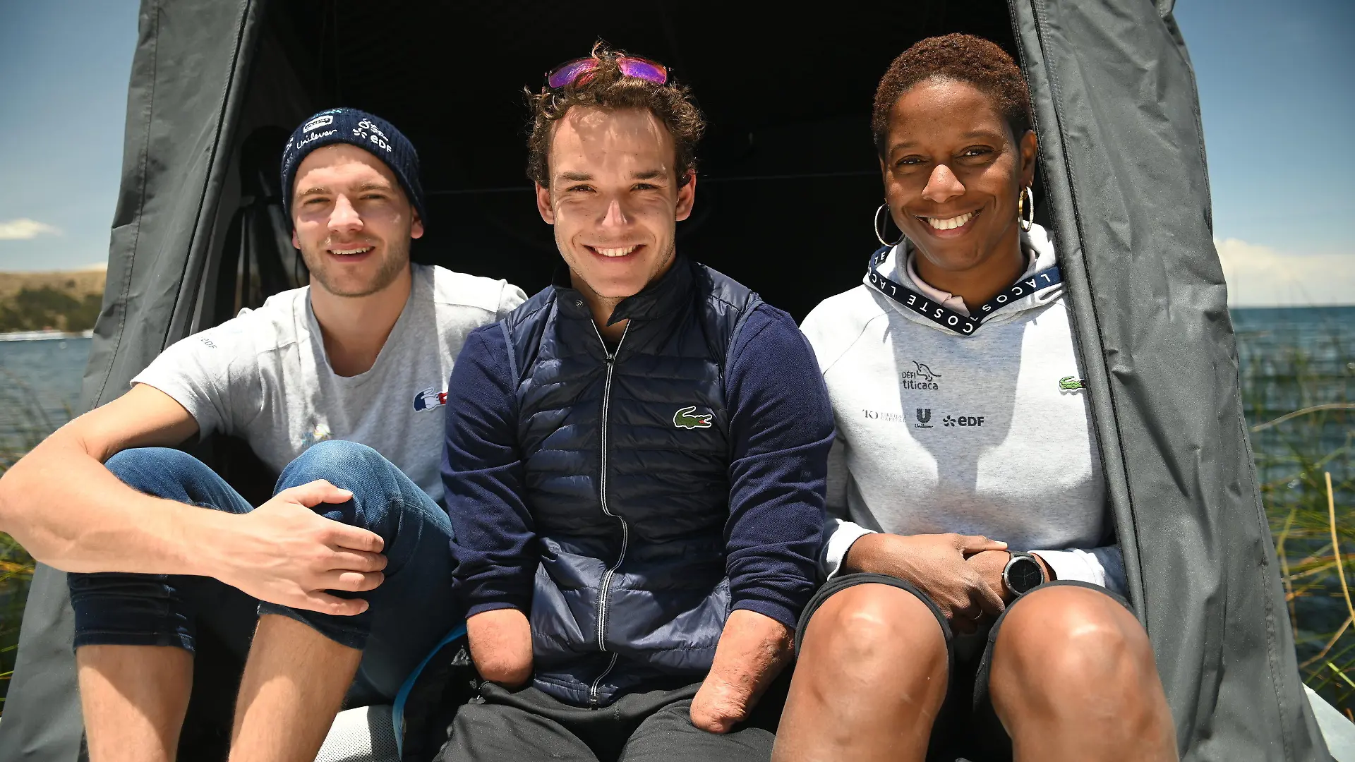 09.11.2021, Bolivien, Copacabana: Matthieu Witvoet (l-r), der sich als «Öko-Abenteurer» definiert, Theo Curin, Paralympics-Schwimmer, und Malia Metella, französische Athletin, lächeln vor dem Start einer Schwimmaktion am Tititcacasee. Die Gruppe hat sich als Ziel vorgesetzt, 122 Kilometer durch den auf einer Höhe von 3812 Metern über dem Meeresspiegel liegenden See zu schwimmen - eine Herausforderung, die «zwischen acht und zehn Tage» dauern könnte. «Der Wunsch, mich selbst zu übertreffen, einen noch verrückteren Traum zu erreichen; zu zeigen, dass durch mentale Stärke alles möglich ist - unabhängig der körperlichen Einschränkung... das ist die Botschaft, die ich vermitteln möchte», sagte Courin. Foto: Radoslaw Czajkowski/dpa +++ dpa-Bildfunk +++