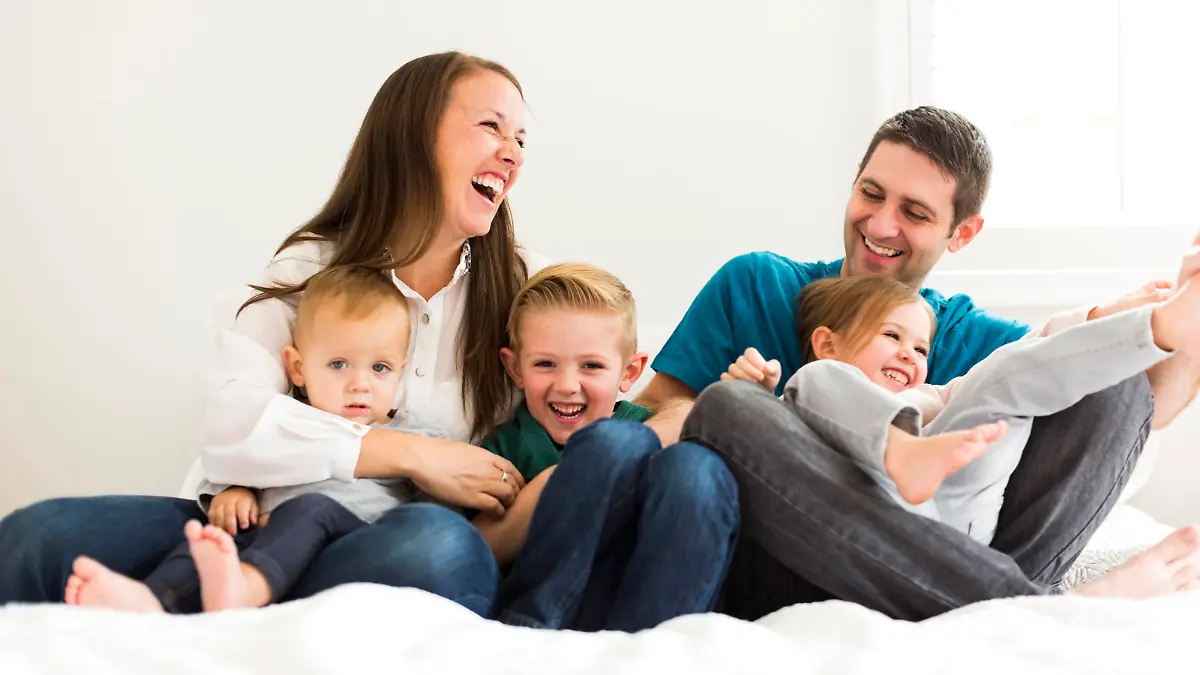 Family with three children (2-3, 4-5) laughing on bed Keine Weitergabe an Drittverwerter.